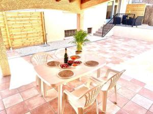 - une table blanche avec 2 chaises et une bouteille de vin dans l'établissement L'Evasion - Climatisé - Jardin - Plage - Jacuzzi, à Perpignan