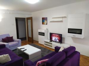 uma sala de estar com sofás roxos e uma televisão em HanaDi Apartment em Sarajevo