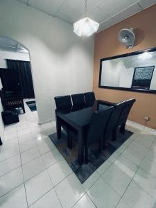 a dining room with a black table and chairs at Daliya Homestay Ulu Tiram JB in Ulu Tiram