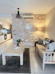 a living room with a couch and a brick wall at Wild Olive 65 Farmhouse Style in Windhoek