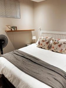 een slaapkamer met een bed met witte lakens en kussens bij Wild Olive 65 Farmhouse Style in Windhoek