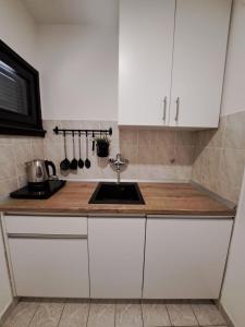 a kitchen with white cabinets and a sink at Family Resort Urania in Baška Voda