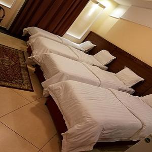 een rij witte bedden in een hotelkamer bij جوار البيت مكة in Mekka