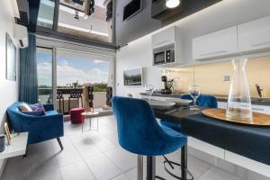 a kitchen and living room with blue chairs and a table at Village Naturiste R4N - Le Bocca Port Nature Coursive Luxe in Cap d'Agde