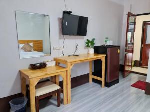 a room with a desk and a tv on a wall at Mookboonchu Guesthouse ,Kohmook Trang in Ko Mook