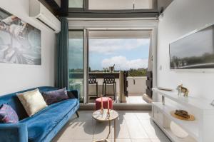 - un salon avec un canapé bleu et une grande fenêtre dans l'établissement Village Naturiste R4N - Le Bocca Port Nature Coursive Luxe, au Cap d'Agde