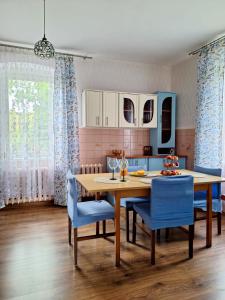 cocina con mesa de madera y sillas azules en Domek przy Maja, en Milicz
