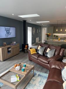 a living room with a brown leather couch and a table at The Cosy Coo Shed in Forfar