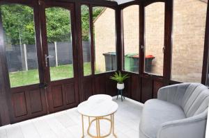 a screened in porch with a chair and a table at Modern 3 bedroom house- 2 parking spaces- near central MK in Shenley Lodge