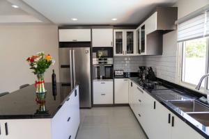een keuken met witte kasten en een vaas met bloemen op het aanrecht bij Spacious 3BR Home with Own Private Cozy Pool in Koolbaai