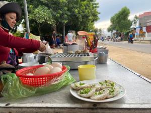 uma mulher a preparar comida numa mesa com um prato de comida em Ninh Chử House em Ninh Hải