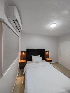 a bedroom with a large white bed and two lamps at Cleopetra Hotel in Wadi Musa