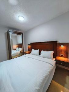a bedroom with a large white bed and a mirror at Cleopetra Hotel in Wadi Musa
