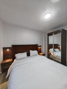 a bedroom with a large white bed and a mirror at Cleopetra Hotel in Wadi Musa