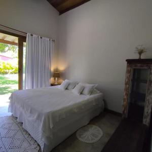 a white bedroom with a bed and a window at Lá em Casa - Guest House in Barra Grande