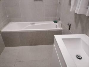 y baño con bañera blanca y lavamanos. en Two bedroom flatlet in Panorama, en Ciudad del Cabo