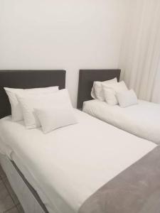 dos camas blancas sentadas una al lado de la otra en una habitación en Two bedroom flatlet in Panorama, en Ciudad del Cabo