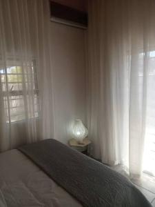 1 dormitorio con 1 cama y ventana con lámpara en Two bedroom flatlet in Panorama, en Ciudad del Cabo