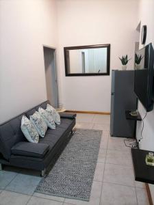 a black couch in a living room with a mirror at Two bedroom flatlet in Panorama in Cape Town
