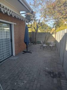 a patio with an umbrella and a table and chairs at Two bedroom flatlet in Panorama in Cape Town