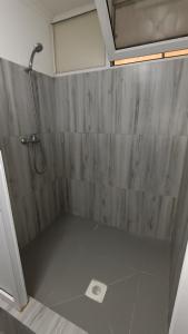 een douche in een badkamer met een betonnen muur bij The Mini-hotel on Mukanova St in Alma-Ata