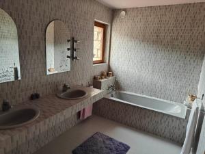 y baño con 2 lavabos, bañera y espejo. en Maison spacieuse idéale pour vacances en famille, en Montbrun-les-Bains