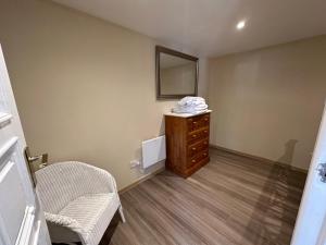 a room with a dresser and a mirror and a chair at Beautiful Cottage by The River Trent in Dunham