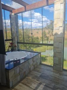 una vasca da bagno in una stanza con una grande finestra di Sítio defronte Lagoa Lagoa na Serra do Cipó a Jaboticatubas