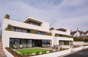 a white house with a lawn in front of it at 1 The Bay - Stunning contemporary flat on the Scottish coast in Coldingham