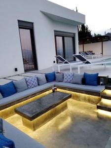 um sofá sentado no topo de um edifício com almofadas azuis em Nafplio Villa, pool & sea view em Tolo