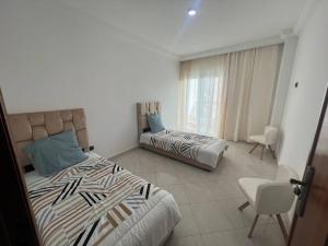 um quarto com 2 camas e uma cadeira em Appartement Haut Standing 3 chambres proche gare et centre ville em Kenitra