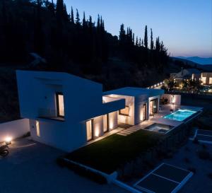 uma casa com piscina à noite em Nafplio Villa, pool & sea view em Tolo