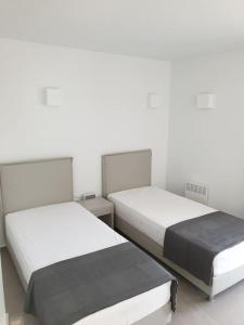 Duas camas num quarto com paredes brancas em Nafplio Villa, pool & sea view em Tolo