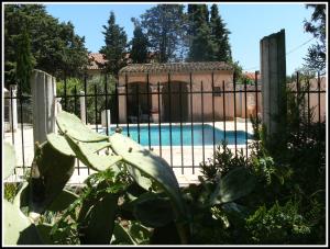 a fence with a pool in front of a house at Les jardins du Patriarche Hôtel in Agde