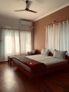 a bedroom with a large bed with white curtains at hello beach view resorts in Varkala