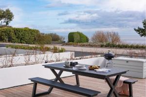 a picnic table on a patio with a view of the ocean at 1 The Bay - Stunning contemporary flat on the Scottish coast in Coldingham