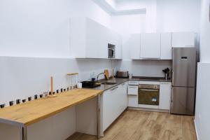 a kitchen with white cabinets and a wooden counter top at Triana Riverside in Seville