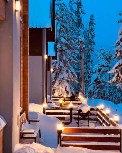 a snowy porch with benches and lights in the snow at Woodland Resort Shkrel in Boge