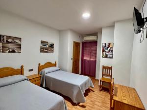 um quarto de hotel com duas camas e uma televisão em Hospederia del Pilar em Valência