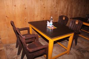 Hotel Mannat Sach Pass في Tisa: طاولة خشبية عليها كراسي وزجاجة ماء