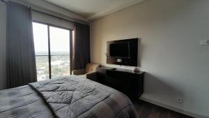 een slaapkamer met een bed en een flatscreen-tv bij Ruby Apartment #22 in Kejayan