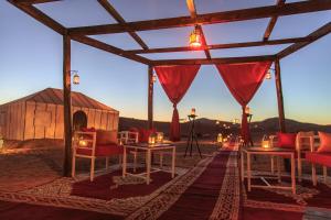 a gazebo with chairs and a table and lights at Tiziri Camp in Merzouga
