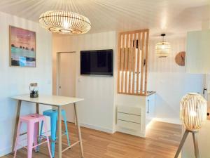 a living room with a table and chairs and a kitchen at Studio face mer pieds dans l’eau in Saint-Hilaire-de-Riez
