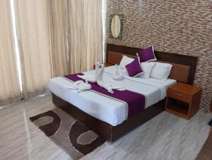 a bedroom with a large bed with purple and white pillows at Gold India Beach Resort in Havelock Island