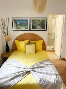 Schlafzimmer mit einem Bett mit gelber Bettwäsche und Kissen in der Unterkunft Studio 2 personnes à 10 minutes de Paris in Gennevilliers