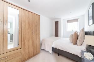 a bedroom with a bed and a large wooden cabinet at The Wandsworth Flat in Bromley