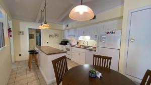 a kitchen with a table and a kitchen with white appliances at SEA COTTAGE APARTMENT Duplex in Jekyll Island