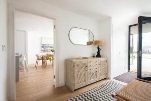 a white living room with a mirror and a dresser at 1 The Bay - Stunning contemporary flat on the Scottish coast in Coldingham
