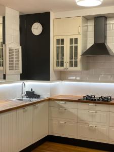 a kitchen with white cabinets and a clock on the wall at Family apartment on Saska Kępa in Warsaw