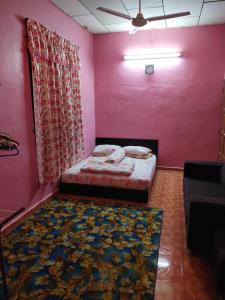 een slaapkamer met een bed en een roze muur bij Iman homestay in Lunas